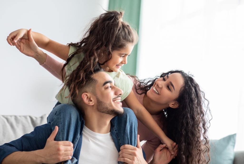 peaceguard-hero-min Happy family laughing together at home representing PeaceGuard insurance
